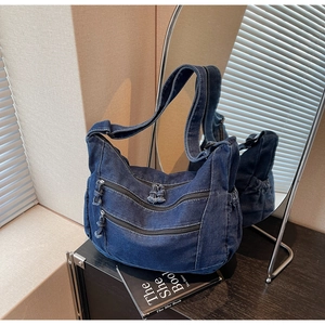 Detailed shot of dark blue washed denim tote with triple front zippers and side drawstrings