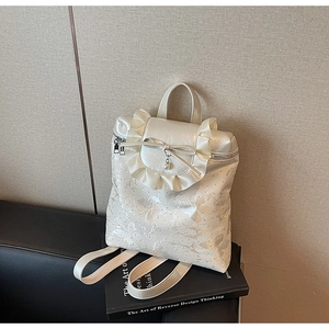 Detail of cream bucket bag featuring butterfly jacquard texture and ruffled bow design