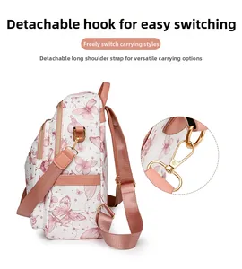 Détail de la bandoulière rose amovible avec crochet en métal doré sur le sac à dos papillon