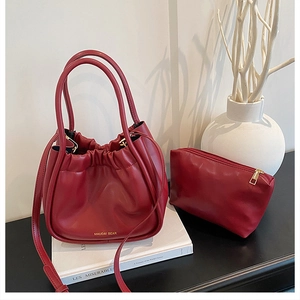 Detail of burgundy drawstring bucket bag with gold lettering and matching inner pouch