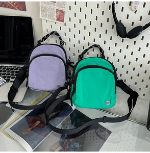 Détail des sacs bandoulière en nylon imperméable violet et vert avec poignées tissées