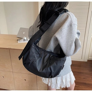 Detail of black nylon messenger bag with adjustable strap and dual vertical zippers