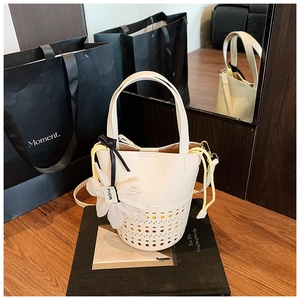 Détail du sac seau ajouré crème avec doublure jaune et breloque florale élégante