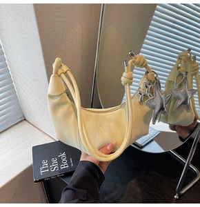 Detail of cream crescent shoulder bag with silver star and balloon dog pendants
