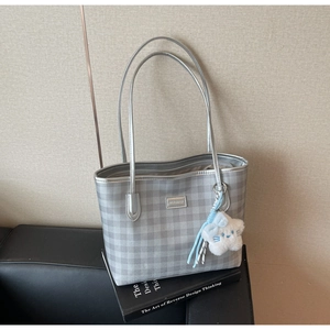 Close-up of silver checkered tote bag featuring a brand plaque and plush star charm