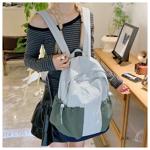 Detail of grey and olive green patchwork nylon backpack with drawstring side pockets