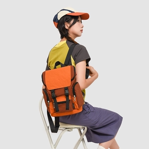 Detail of a color-block canvas backpack with dual buckle closure and side zipper pockets
