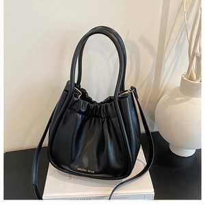 Detailed view of the pleated black leather cloud bag with golden brand lettering logo