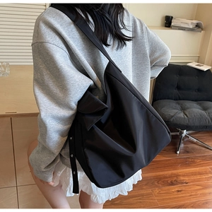 Detail of adjustable silver eyelet strap on a minimalist black crescent crossbody bag