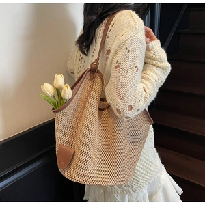 Détail du cabas en paille tissée avec garniture en cuir marron et poignée chic