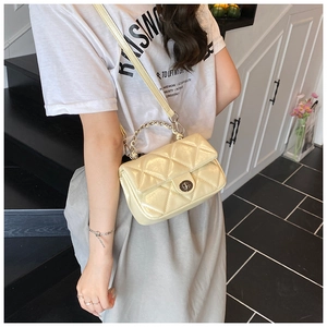 Close-up of cream yellow quilted mini crossbody bag with metal chain handle and twist lock