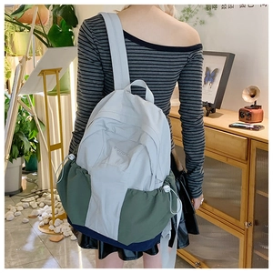 Detail view of a color-block casual backpack with drawstrings and side storage pockets
