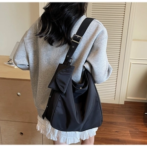 Detail of nylon hobo tote bag featuring a wide adjustable strap and small clip-on pouch