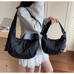 Detail showing two sizes of black nylon crescent crossbody bags with multiple pockets