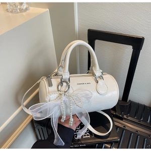 Détail du sac tonneau en cuir blanc avec breloque nœud en perles et imprimé mode