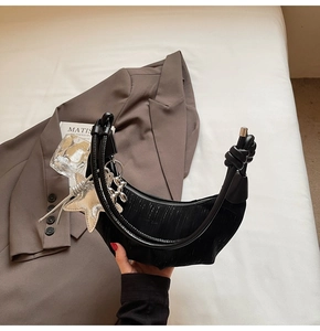 Close-up of black pleated hobo bag with silver star and balloon dog charm accessories
