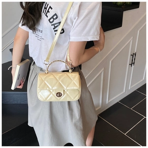 Close-up of quilted diamond pattern and metal twist lock on a beige leather handbag