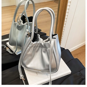 Detail of silver metallic bucket bag with drawstring pleated texture and slim strap