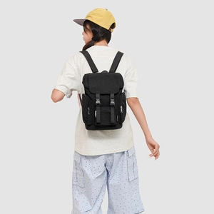 Detail of black utility backpack with buckle flap and multiple zip pockets shown on model
