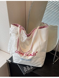 Large cream canvas tote bag with red French lettering and striped shoulder straps