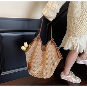 Détail macro du sac cabas en paille tissé main avec bordure et bandoulière en cuir brun