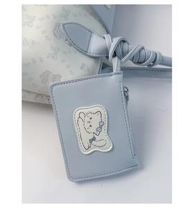 Detail of light blue faux leather bag featuring cute cat prints and a kitten shaped charm