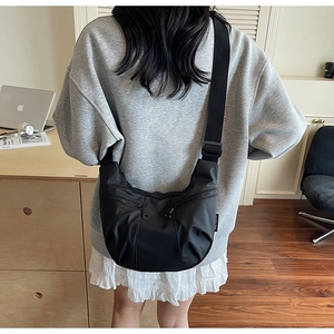 Fashionable black crescent shoulder bag shown on model in a cozy studio setting
