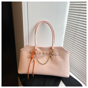 Detail of light pink leather tote bag featuring golden metal chain and woven rope accent