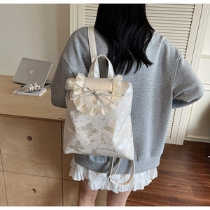 Close-up of white bucket bag featuring elegant butterfly prints and pearl bow detail