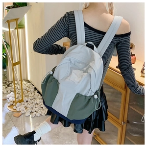 Detailed side view of nylon backpack with tricolor patchwork and drawstring side pockets