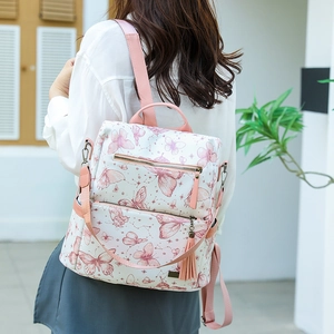 Detailed view of butterfly print backpack featuring pink leather straps and tassel charms