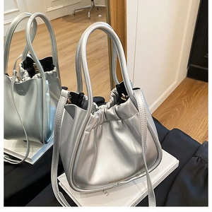 Detailed mirror reflection of silver metallic bucket bag with MAUDAI BEAR logo and drawstring