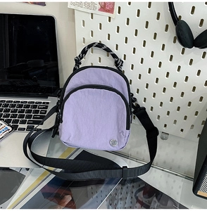 Détail du sac bandoulière en nylon violet imperméable avec fermetures éclair et poignées