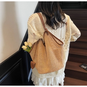 Detail of woven straw tote bag with brown leather straps and yellow tulips inside