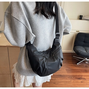 Detail of black nylon crescent crossbody bag with multiple zippers and adjustable strap