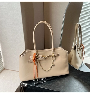Beige tote bag detail showing orange rope and gold chain on wood cabinet with mirror
