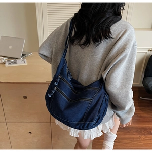 Close-up of vintage blue denim crossbody bag with multiple zipper pockets and workwear style
