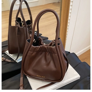 Detail of dark brown leather bucket bag featuring drawstring pleats and gold logo