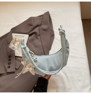 Detail of light blue hobo bag with knotted handle and silver star charm on art book
