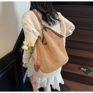 Détail d'un sac cabas en paille tissé avec anses en cuir marron et motif maille