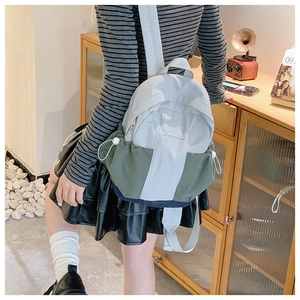 Detail view of a color-block mini backpack with olive green trim and side drawstrings