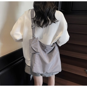 Detail of adjustable wide shoulder strap and side pocket on a grey nylon tote bag
