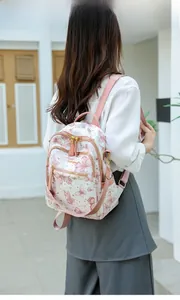 Détail d'un sac à dos blanc avec imprimé papillon porté par un mannequin en extérieur