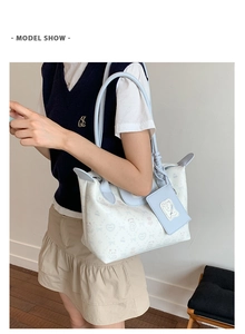 Detail of white tote bag with bear print, blue trim, and matching small square pouch