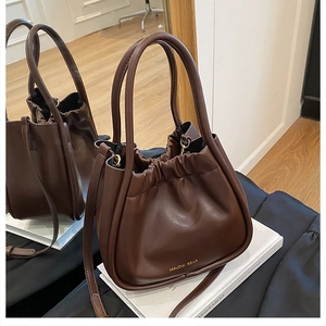 Detail of dark brown leather bucket bag with drawstring pleats and gold logo branding