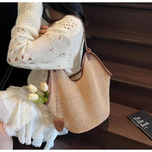 Détail du sac cabas en paille tissée avec des lanières en cuir marron et texture naturelle