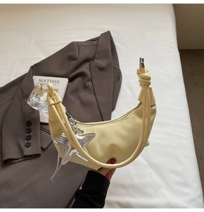 Detail of light yellow crescent hobo bag with star charm and leather texture