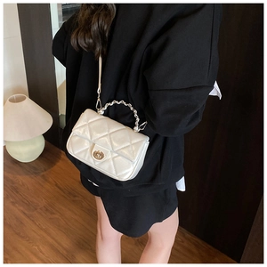 White quilted crossbody bag with gold twist lock and chain handle shown on shoulder