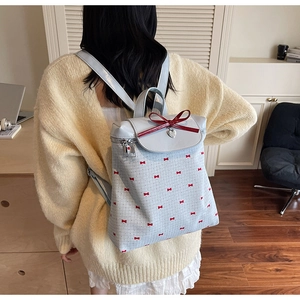 Rear view of a light blue bow-knot bucket backpack worn by a model in a cozy setting