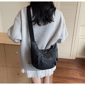 Detailed view of black nylon crescent bag with double zippers worn by a model